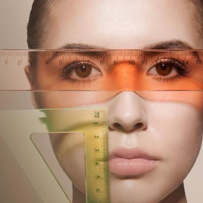 Κοντινό πλάνο γυναικείου προσώπου με διάφανους χάρακες τοποθετημένους πάνω του, επισημαίνοντας τη συμμετρία των χαρακτηριστικών. 